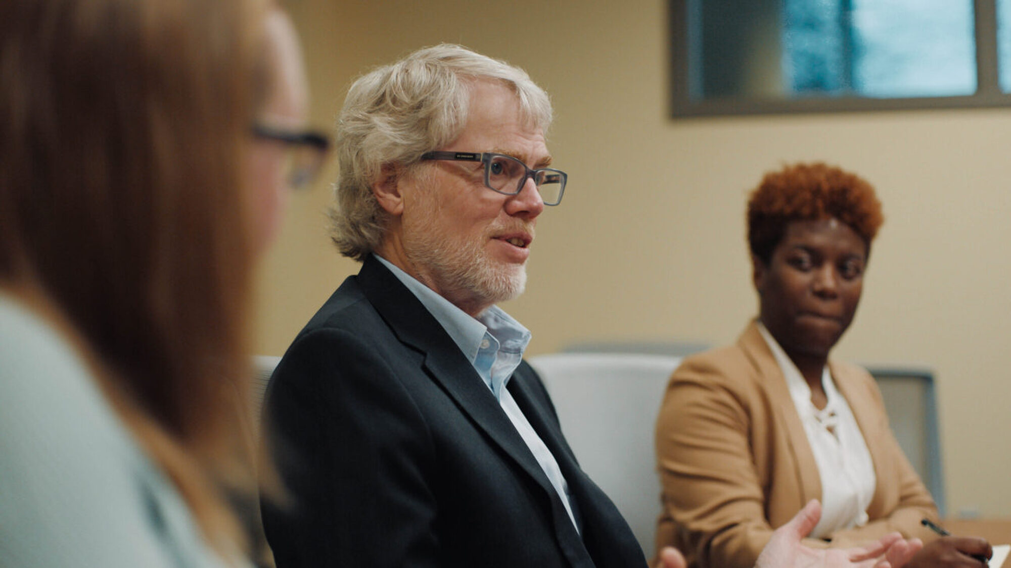 Three people in conversation around a conference table.