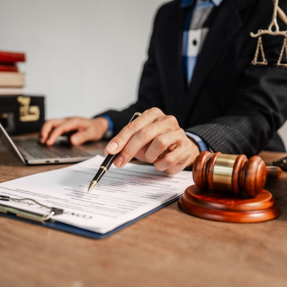 Hands on computer and paper near a judge's gavel.