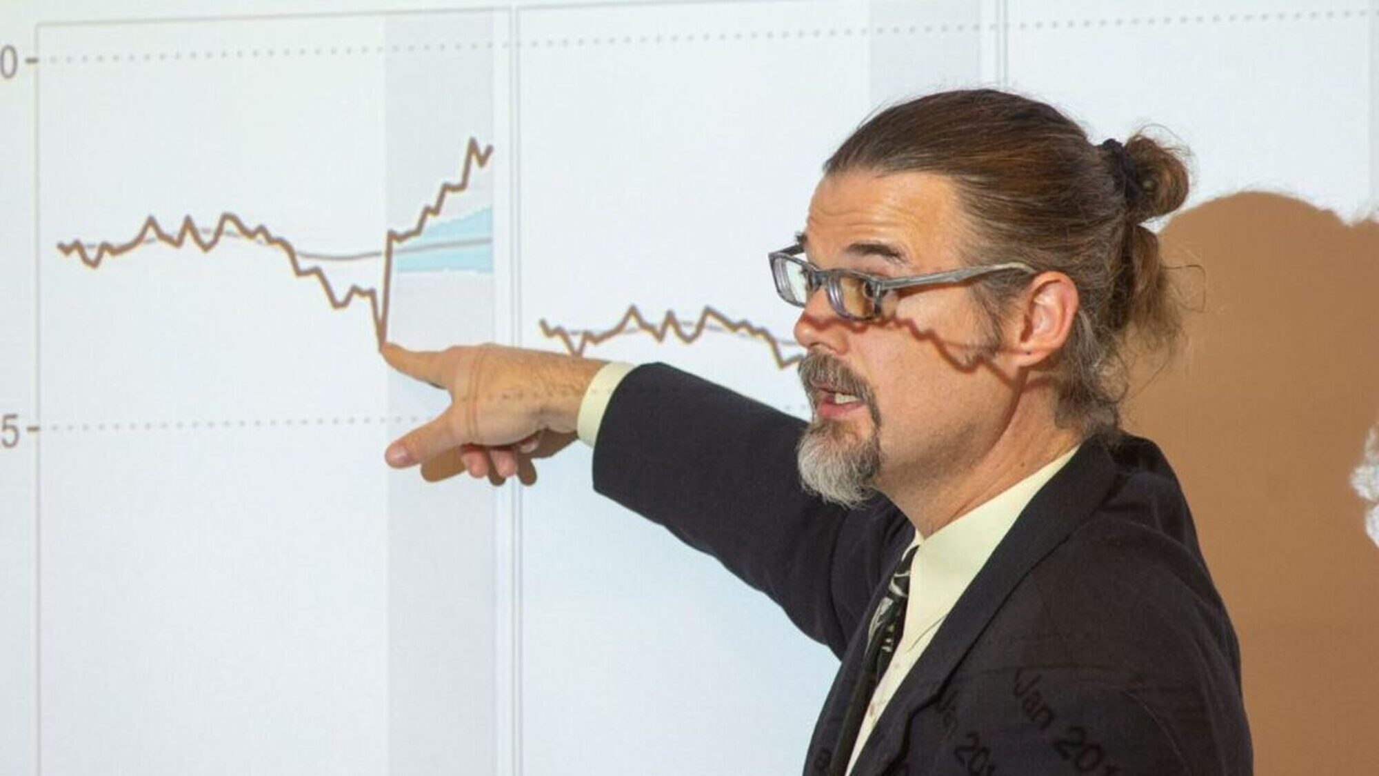 A man presenting jail booking data on a large screen.